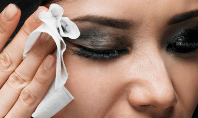 Young woman wiping off make-up, high section, close-up