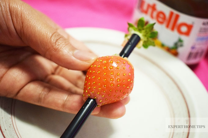 Strawberry pierced by straw and Nutella jar