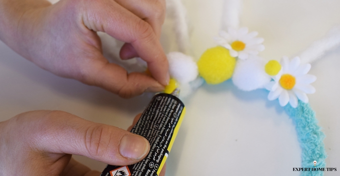 sticking fake flowers and pompoms onto easter headband