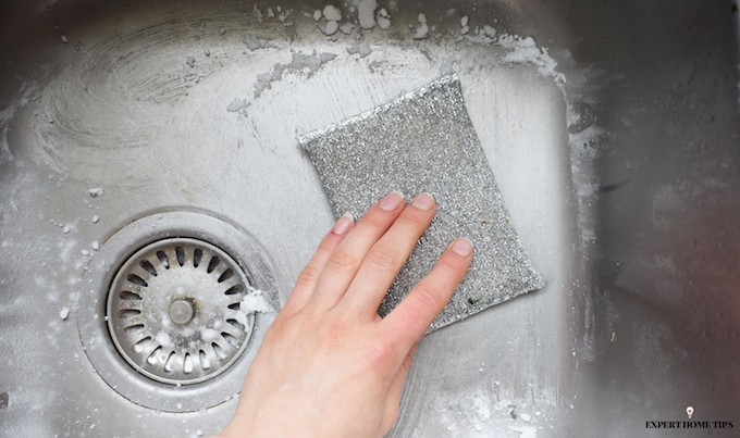 scrubbing a stainless steel sink with DIY cleaning product