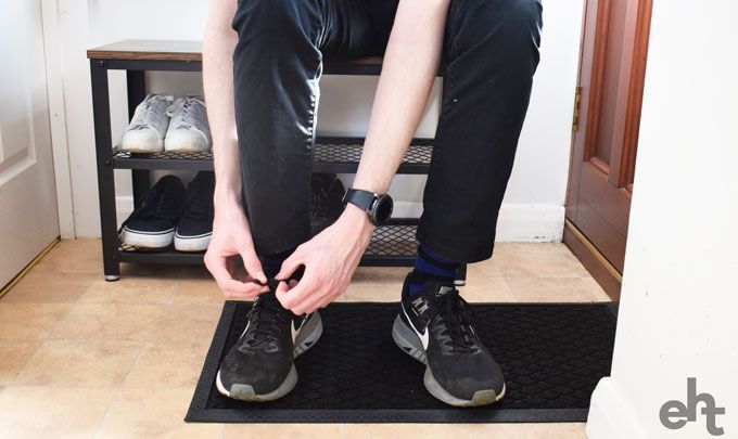 man tying shoelaces sat on a shoe storage bench